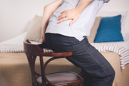 Back pain, kidney inflammation, man suffering from backache at home