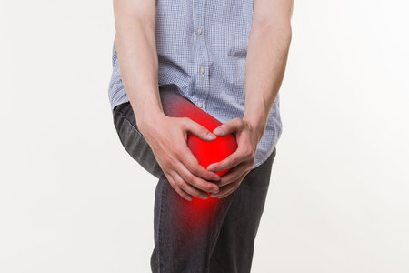 Man with pain in knee, studio shot on white background, painful area highlighted in red