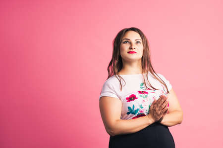 Pensive plus size model on pink background, body positive conceptの写真素材