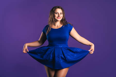 Happy plus size model in blue dress on purple background, body positive conceptの写真素材