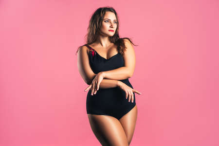 Sexy plus size fashion model in black one-piece swimsuit, fat woman in lingerie on pink background, body positive conceptの写真素材