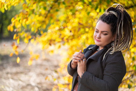 Sad woman with dreadlocks outdoors in autumn, youth culture concept