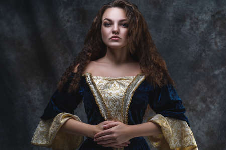 Beautiful woman in renaissance dress on abstract dark background, studio shotの写真素材