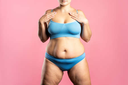 Fat woman in blue underwear on pink background, overweight female body, studio shotの写真素材