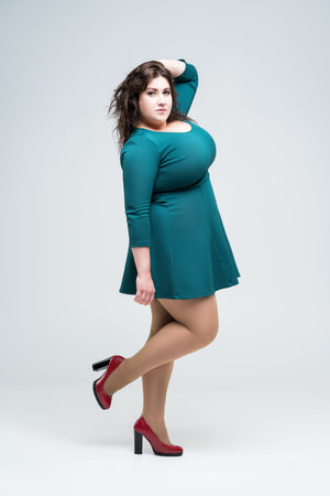 Sexy plus size fashion model in green dress, fat woman on gray background, body positive concept, full length portraitの写真素材