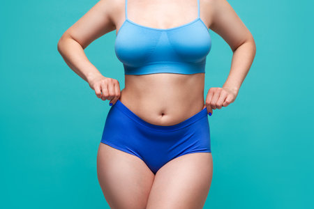 Plus size model in blue underwear on turquoise background, body positive conceptの写真素材