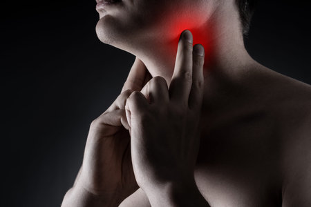 Sore throat, men with pain in neck on black background, painful area highlighted in redの写真素材