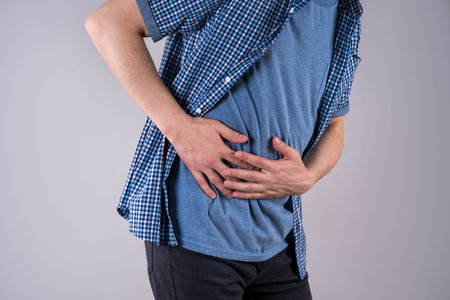 Man with abdominal pain, stomach ache on gray background, studio shotの写真素材