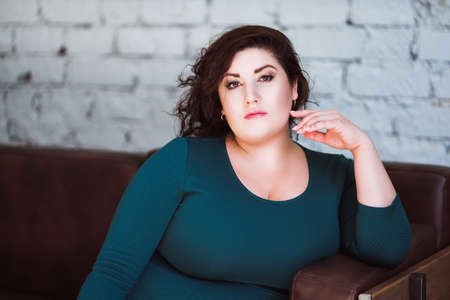 Plus size fashion model in green dress in the interior, fat woman at home, body positive conceptの写真素材