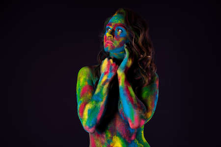 Bright colorful body art on black background, sexy nude woman painted with powder paints, studio shotの写真素材