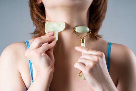 Roller massager and gouache scraper, facial massage and lifting on gray backgroundの写真素材