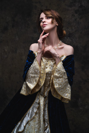 Beautiful sexy woman in renaissance dress on abstract dark background, studio shotの写真素材