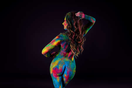 Bright colorful body art on black background, sexy nude woman painted with powder paints, studio shotの写真素材