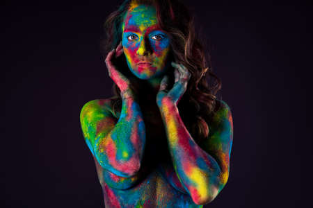 Creative makeup, bright colorful body art on black background, sexy nude woman painted with powder paints, studio shotの写真素材