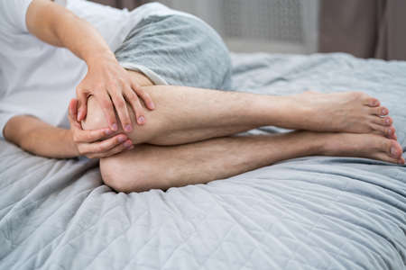 Knee pain, man suffering from ache in the home interior, health problems conceptの写真素材