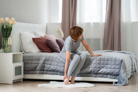 Woman's leg hurts, pain in the foot, massage of female feet at home, health problems conceptの写真素材