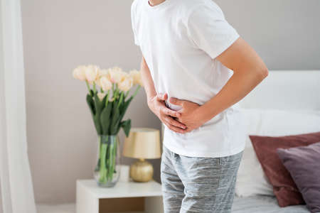 Stomach ache, man with abdominal pain suffering at homeの写真素材
