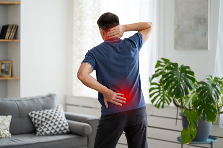 Back pain, man with backache at home, health problems concept