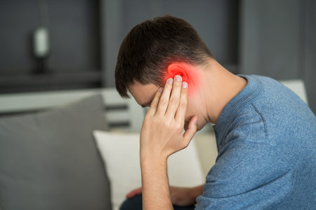 Man with earache, ear pain at home, painful area highlighted in red
