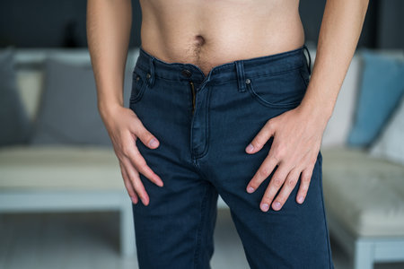 Man in blue jeans at home, diet and overeating concept