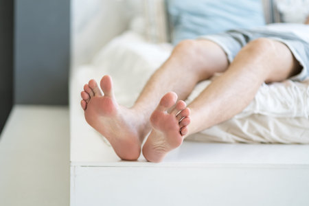 Tired man resting after work at home, male feet, body care concept at home interiorの写真素材
