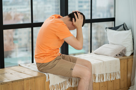 Headache and migraine, man with head pain in home interior, health problems conceptの写真素材