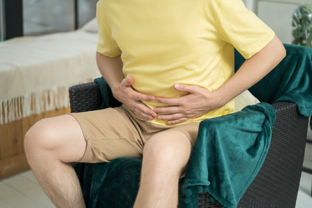 Stomach ache, man with abdominal pain suffering at home, health problems conceptの写真素材