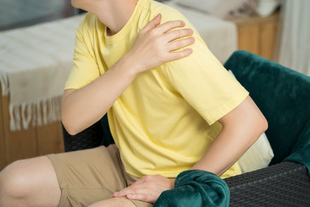 Man with pain in shoulder at home, health problems conceptの写真素材