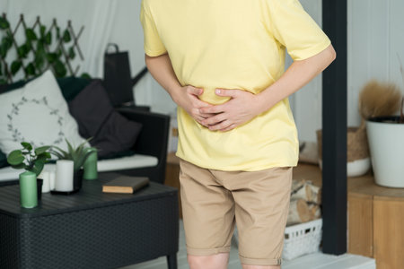 Stomach ache, man with abdominal pain suffering at home, health problems conceptの写真素材