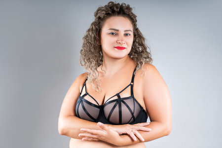 Curvy busty plus size model in push up bra on gray studio background, overweight woman in sexy lingerie, body positive conceptの写真素材