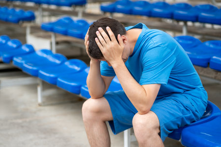 Headache and migraine, man with head pain after workout on a sports ground, health problems conceptの写真素材
