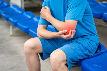 Diseases of the elbow joint, bone fracture and inflammation, athletic man on a sports ground after workout suffering from pain in cubit, healthy lifestyle conceptの写真素材