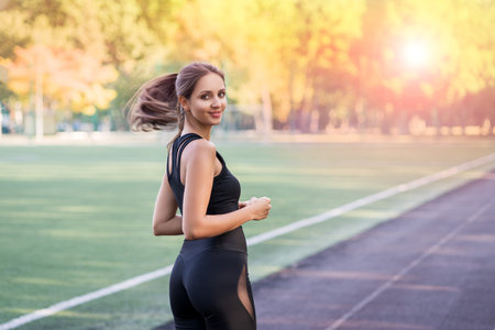 Young fitness woman jogging on a running track in the stadium, sports and recreation, healthy...