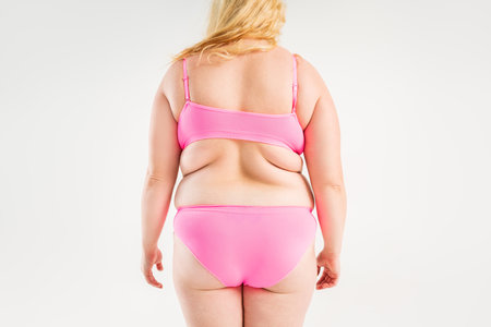 Overweight woman with fat back, hips and buttocks, obesity female body on gray background, studio shotの写真素材