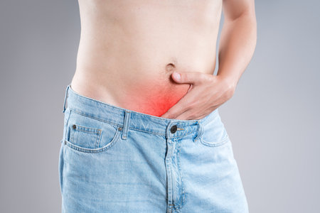 Stomach ulcer, man with abdominal pain on a gray background, symptoms of gastritis, diseases of the digestive system, bladder, pee-pee problem, healthy conceptの写真素材