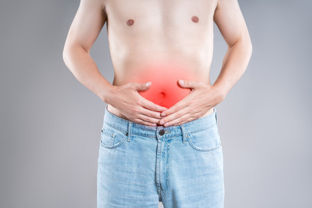 Stomach ulcer, man with abdominal pain on a gray background, symptoms of gastritis, diseases of the digestive system, health problems conceptの写真素材