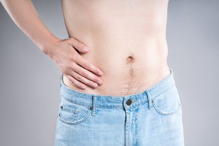 Inflammation of appendicitis, stomach ulcer, man with abdominal pain on a gray background, symptoms of gastritis, diseases of the digestive system, health problems conceptの写真素材