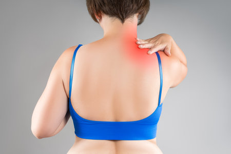 Neck pain, woman suffering from backache, gray studio background, health problems conceptの写真素材