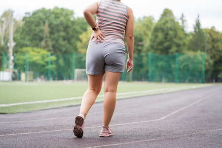 Pain in the hip during training, muscles cramped, massage on a sports ground after workout, health problems conceptの写真素材