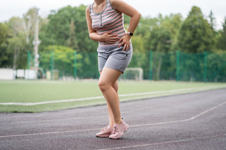 Pain in the hip during training, muscles cramped, massage on a sports ground after workout, health problems conceptの写真素材