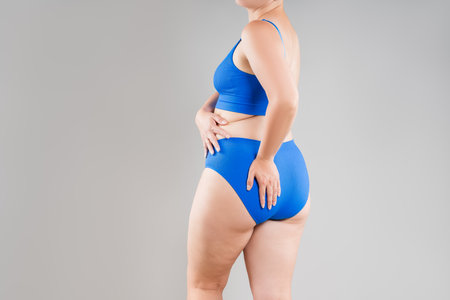 Overweight woman with fat back, hips and buttocks, obesity female body on gray background, studio shotの写真素材
