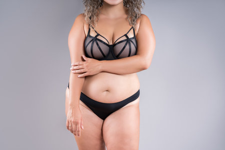 Curvy busty plus size model in push up bra on gray studio background, overweight fat woman in sexy lingerie, fat bodyの写真素材