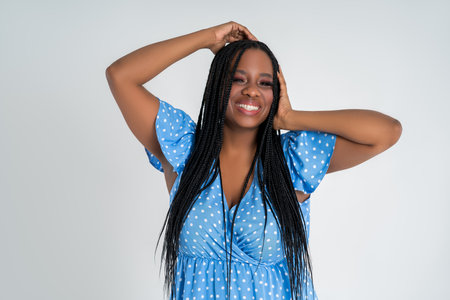 Happy plus size black model in blue dress, beautiful African woman with curvy figure and pigtailed hairstyle, afro braidsの写真素材