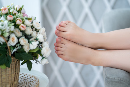 Beautiful female foot closeup, corns and calls on feet, dry cracked skin on legs, barefoot woman relaxing on sofa at homeの写真素材