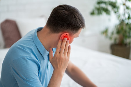 Man with earache at home, ear pain and otitis, health problems conceptの写真素材