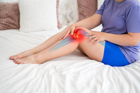 Knee pain, joint inflammation, arthritis and degenerative changes, woman suffering from leg ache and doing self-massage at homeの写真素材