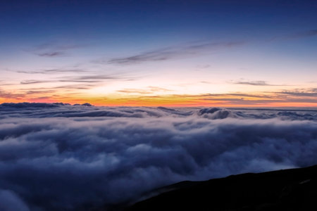 The first rays of light above the clouds, and moments before sunrise at the summit of the dormant...