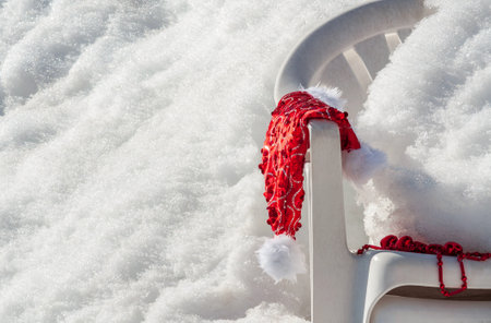 A red New Year's hat hangs on the back of a plastic chair covered with snow.の写真素材