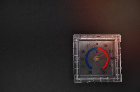 Top view of a dial thermometer on a black background with copy space. Temperature change concept