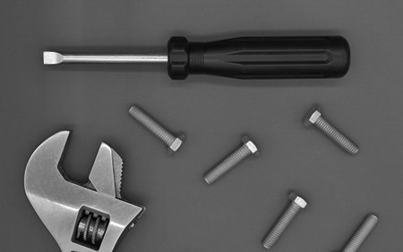 adjustable wrench, screwdriver and bolts on a dark background.
